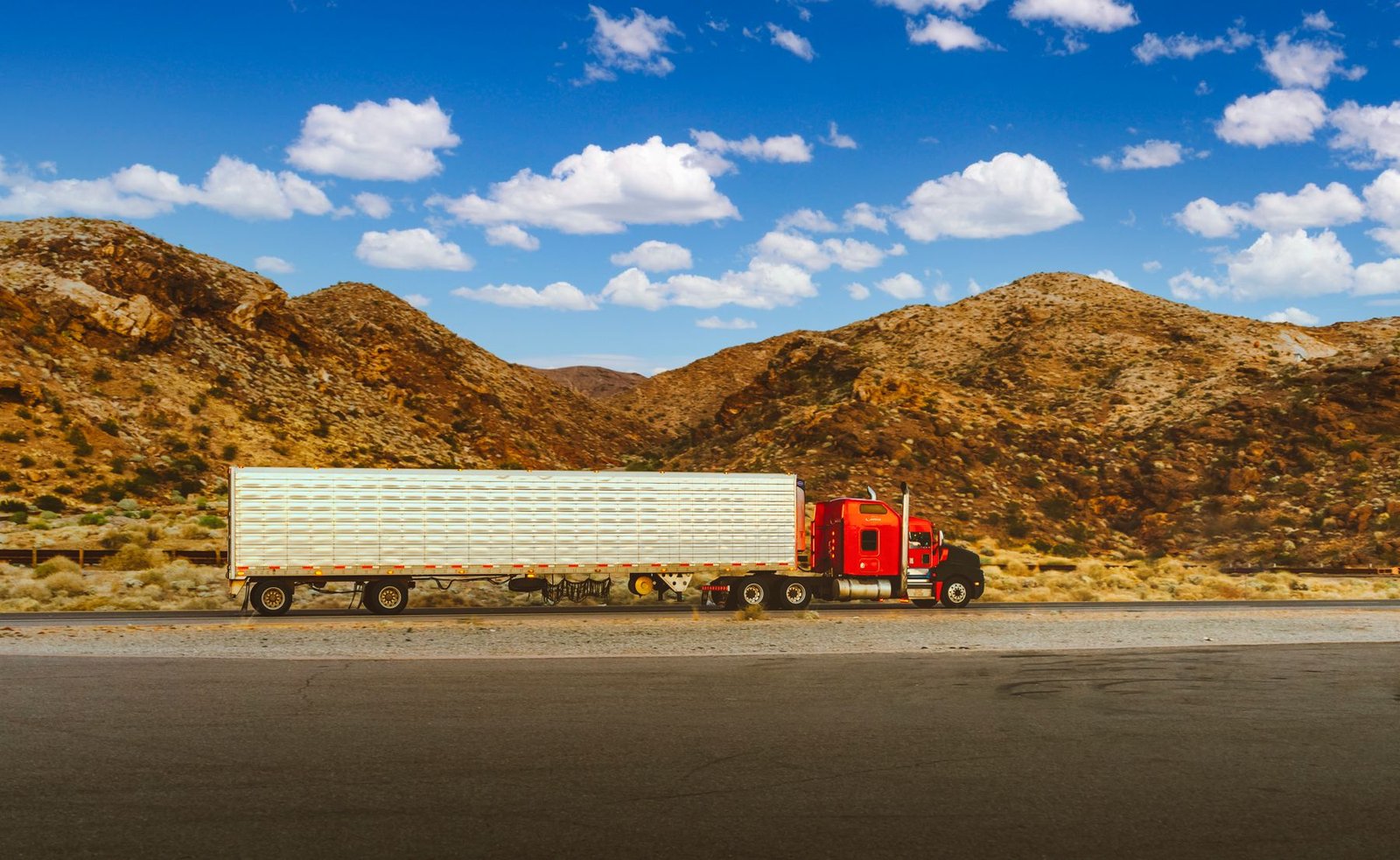 Red semi-truck with trailer on a mountain highway