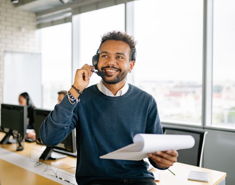 Dispatcher on a headset taking a broker call while holding load documents