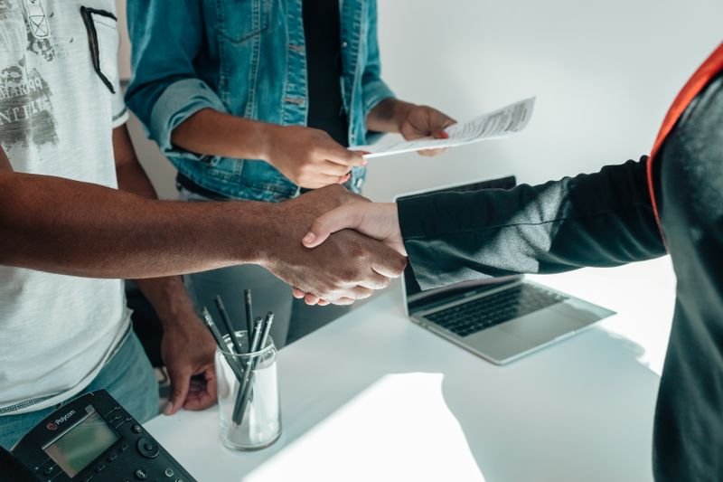 Handshake over carrier setup paperwork and a laptop