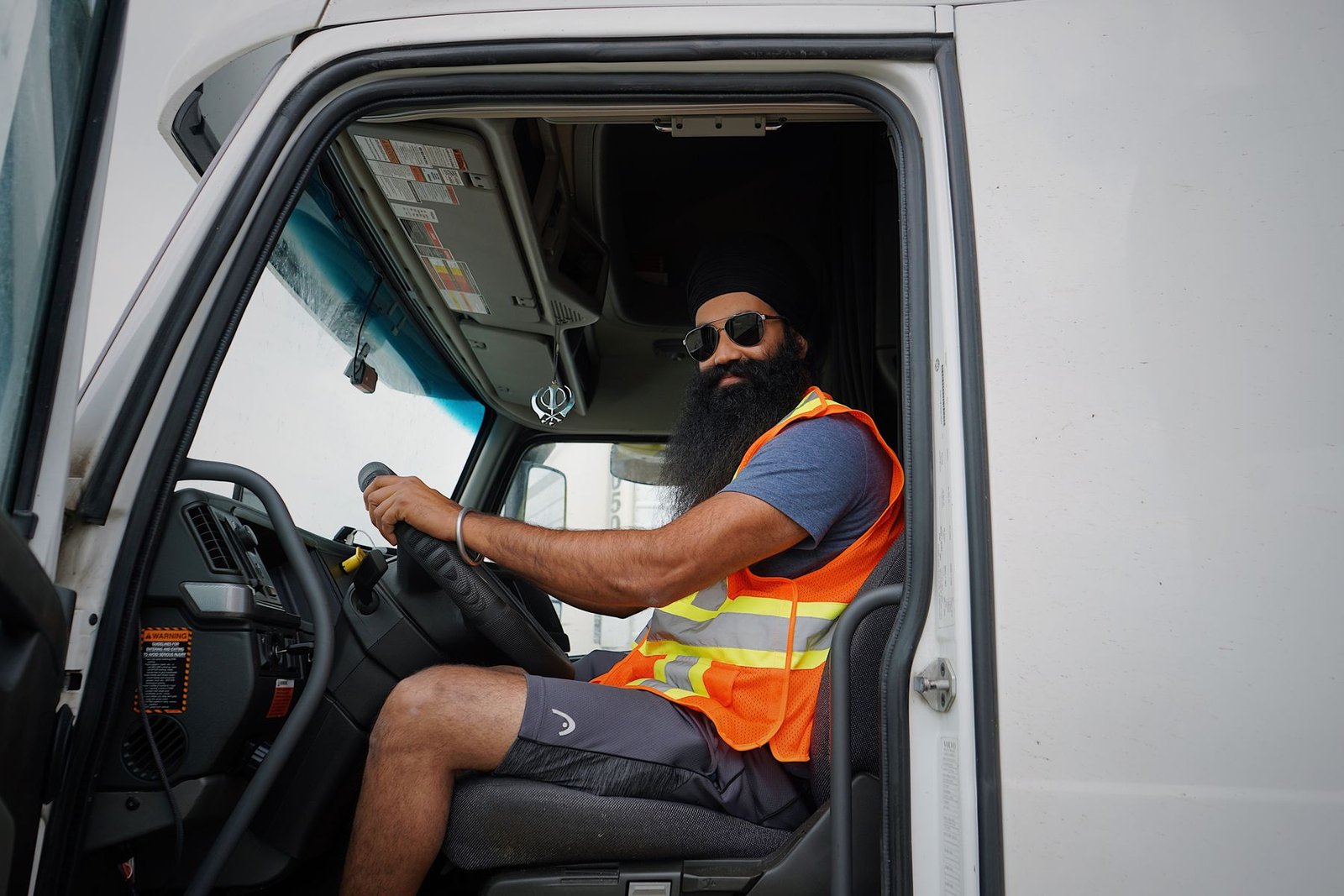 Truck driver in a high-visibility vest sitting at the wheel of his cab